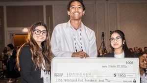three students hold giant $1,500 check made out to Harmoney