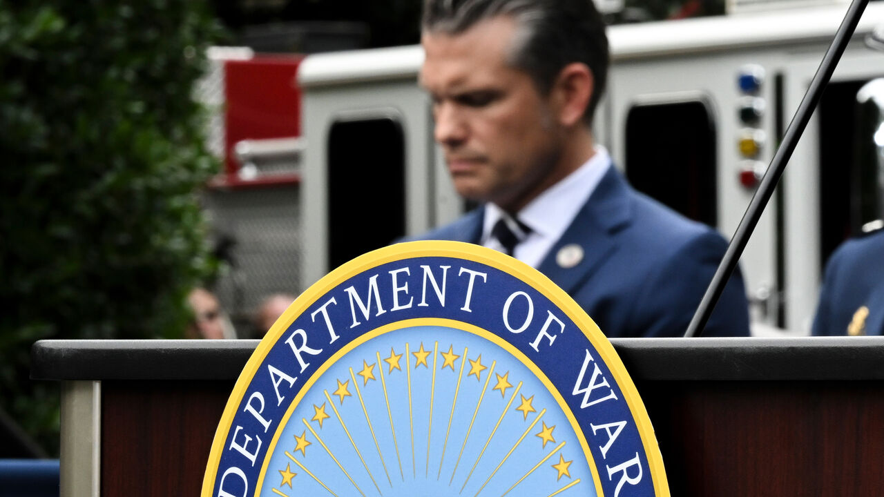 A Department of War emblem in front of Secretary of Defense Pete Hegseth.