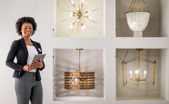 A woman stands before a stunning display of various chandeliers, showcasing their intricate designs and brilliance.
