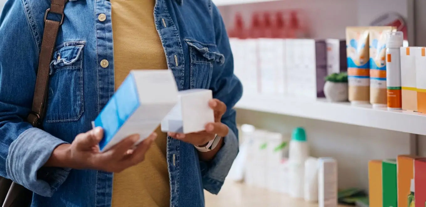 Person in denim selecting skincare products.