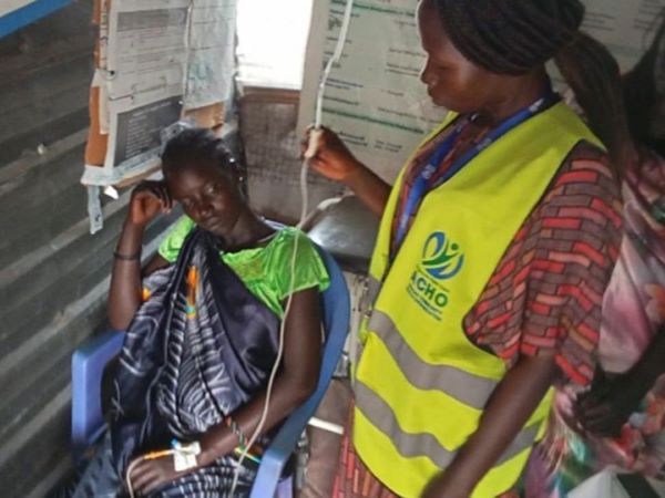 A displaced expectant mother gets an IV from a health care worker supported by CMMB