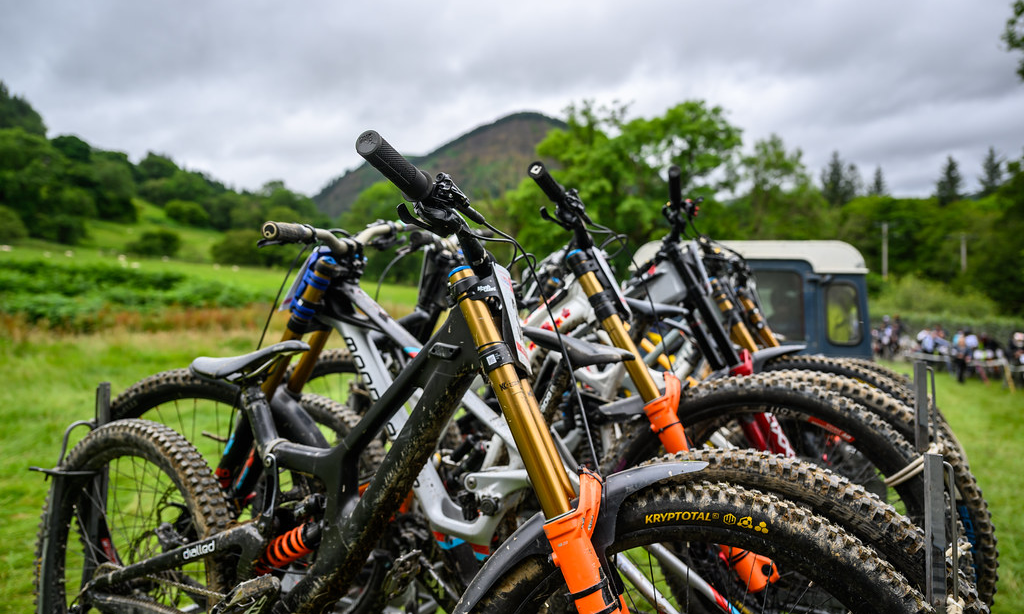 Downhill mountain bikes are stacked onto a trailer at an event setting.