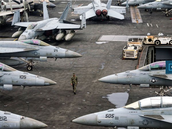 Military base with jets and a soldier walking among them.