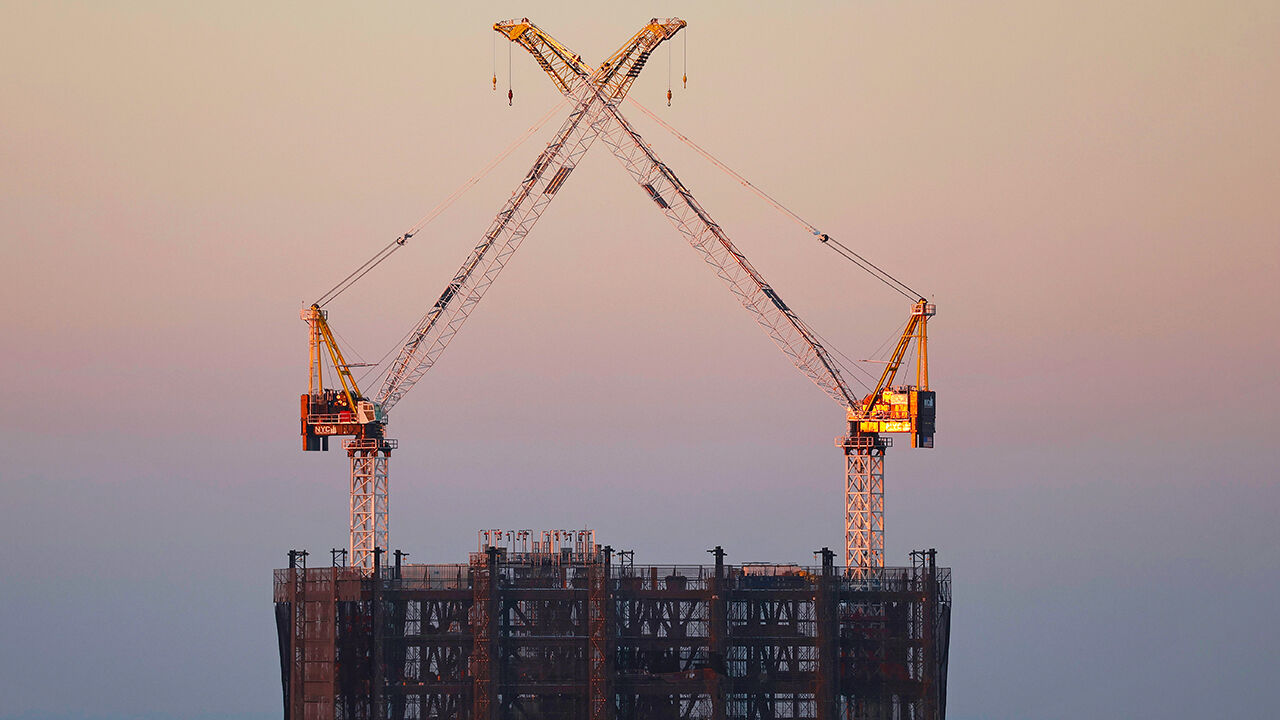 Two cranes stand atop the under-construction building in New York