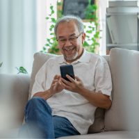 Older adult sitting on a couch using a smartphone to check health information.