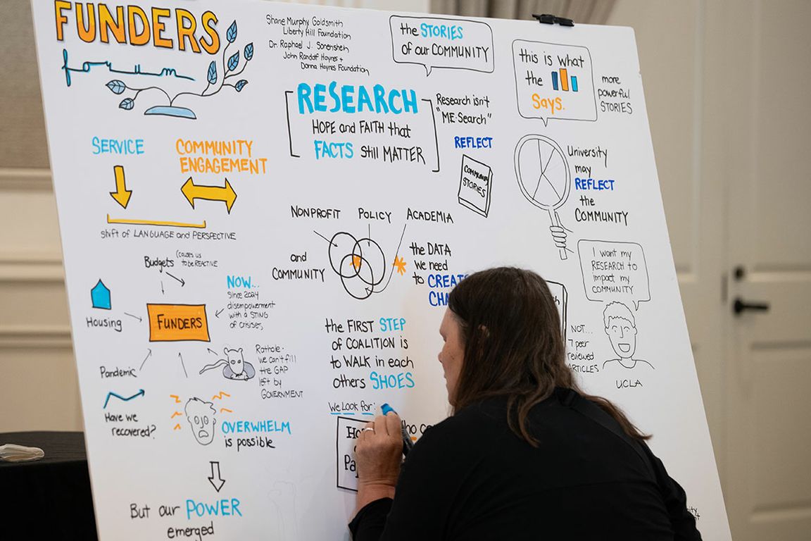 A person writing on a whiteboard featuring hand-drawn text and illustration