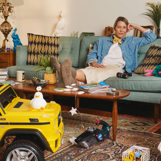 A woman in a cozy living room sits on a sofa with her feet resting on a coffee table.
