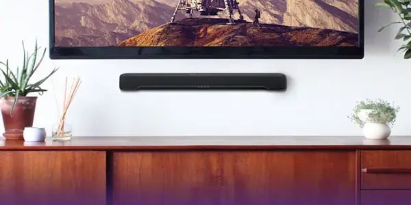 Sound bar mounted on wall underneath a television