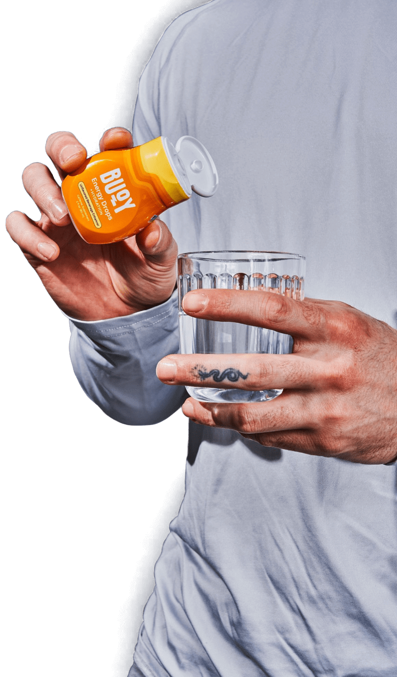 Man holding holding a bottle of Energy Drops and a glass of water.