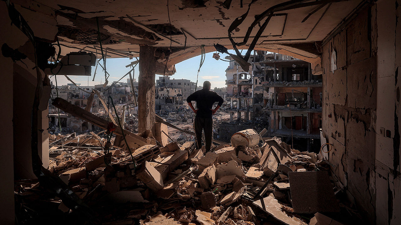 A man stands on an elevated floor in a heavily-damaged building without walls in Rafah