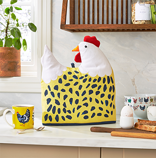 A chicken shaped tea cosy sitting on a kitchen counter, next to some eggs, toast and a cup of tea