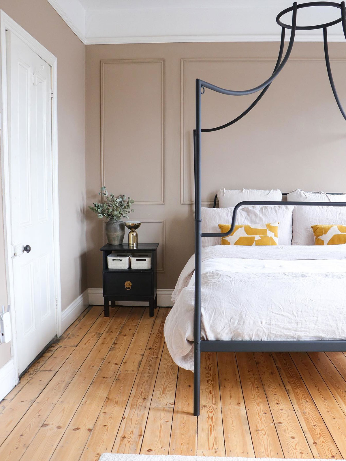 Imagine waking up in this minimalist bedroom that has a sense of calmness and warmth. The warm mid brown walls are reminiscent of gently weathered stone buildings. The stripped pine floor boards bring additional warmth and texture to the room, while the plump pillows and quilt make it hard to imagine wanting to get out of bed, even with all the natural light flooding into the room suggesting a lovely day outside.
