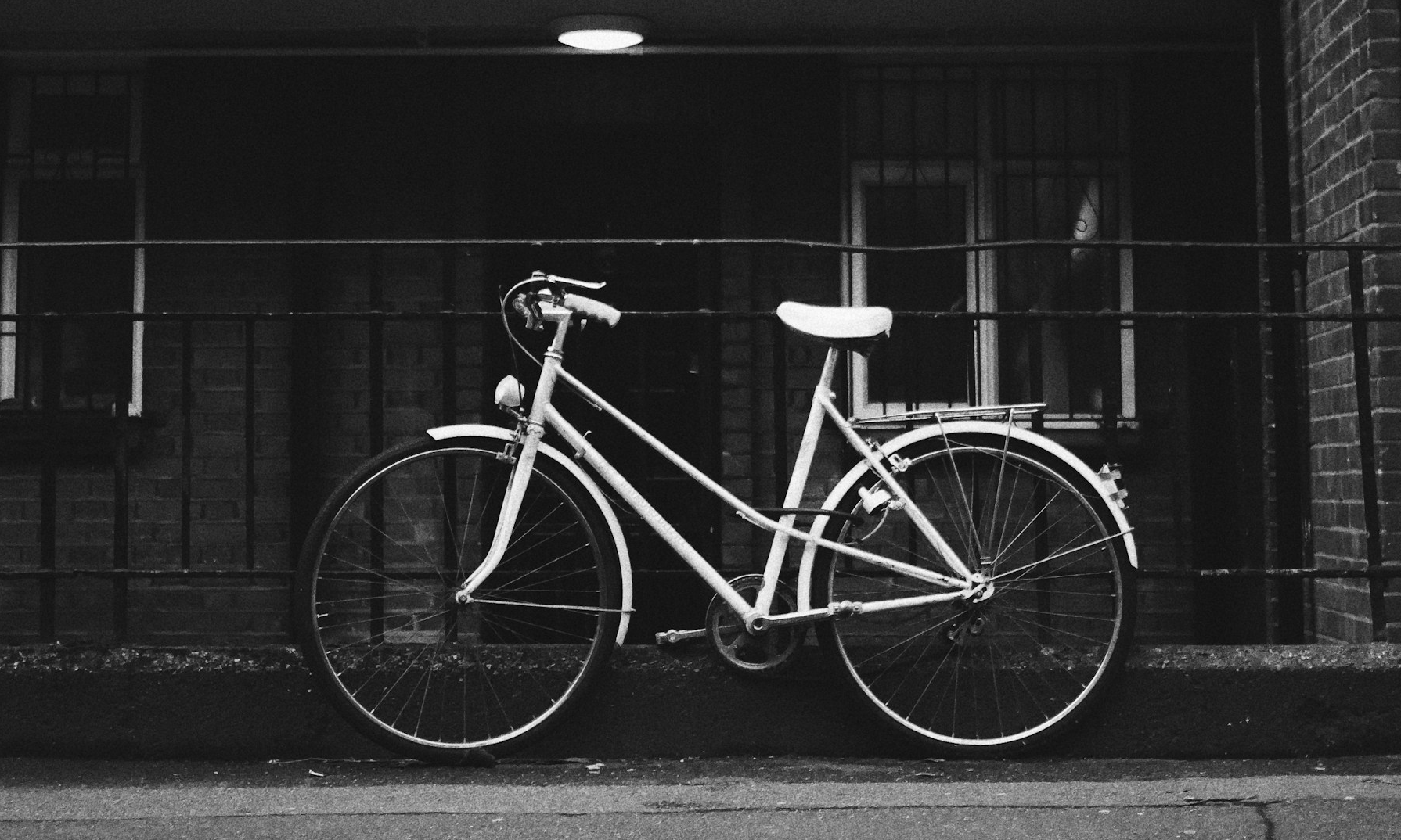 A black and white image of a Dutch city bike locked against metal railings