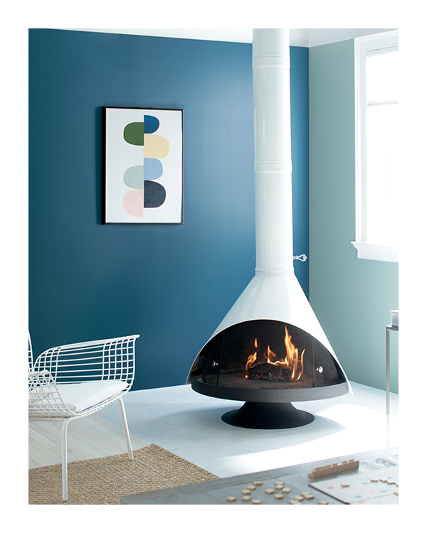 A dark blue painted living room with white ceiling and trim, with a white painted fireplace in the center. 