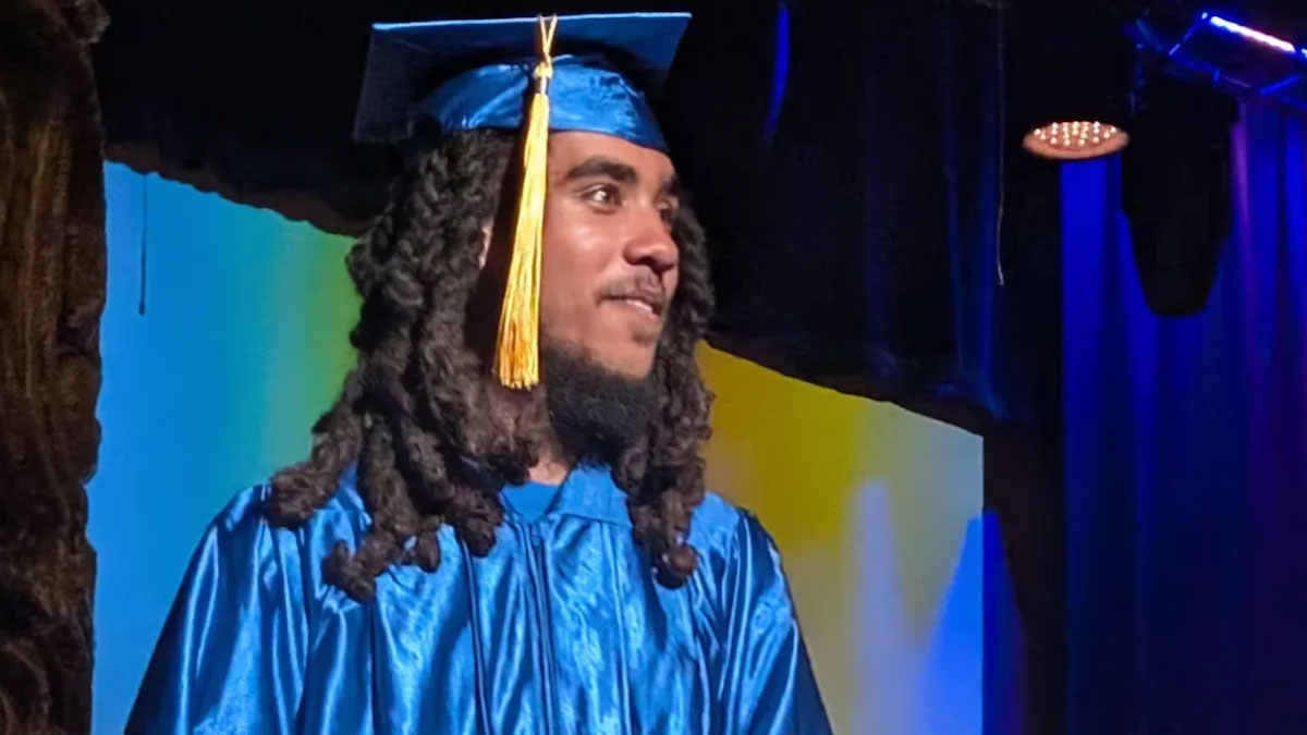 A young man in graduation cap and gown.