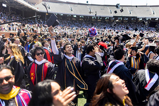 A crowd of graduating students throw their caps for Commencement at Franklin Field.
