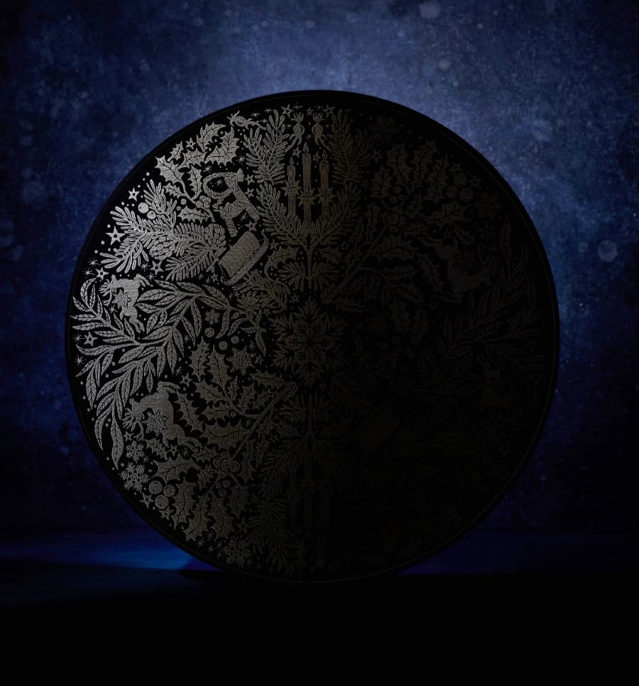 A cylindrical navy box with an intricate botanical design in silver on the lid.