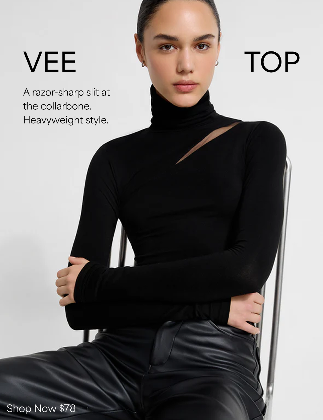 Mily wears the black Vee turtleneck top with a sharp diagonal cutout at the collarbone and black leather pants.