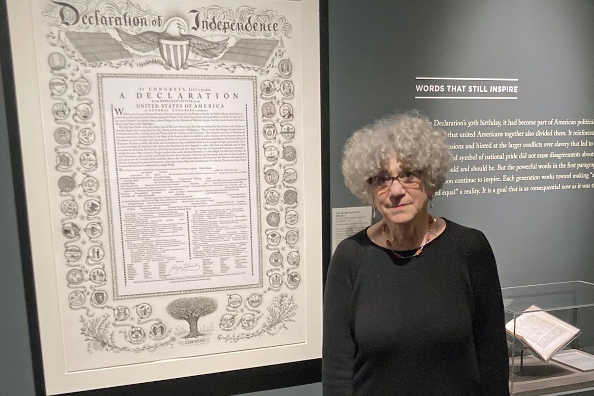 Johanna Drucker stands beside her "Re-Declaration Project" at the American Philosophical Society in Philadelphia, with the large framed artwork displayed behind her as part of the exhibition "These Truths: Declarations of Independence."