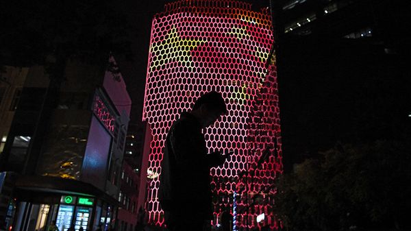 A man looks at his phone near a giant image of the Chinese national flag on the side of a building in Beijing, China