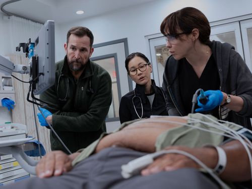 Still from “The Pitt” of three doctors in the hospital treating a patient and looking at a monitor.