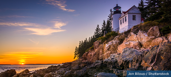 White lighthouse on the rocky shore at sunset in Acadia National Park