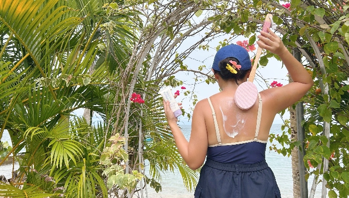 Person applying sunscreen with lotion applicator