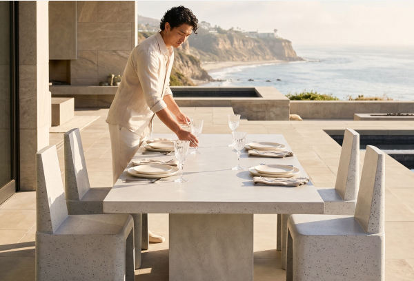 Image of man setting an outdoor dining table on a coastal patio