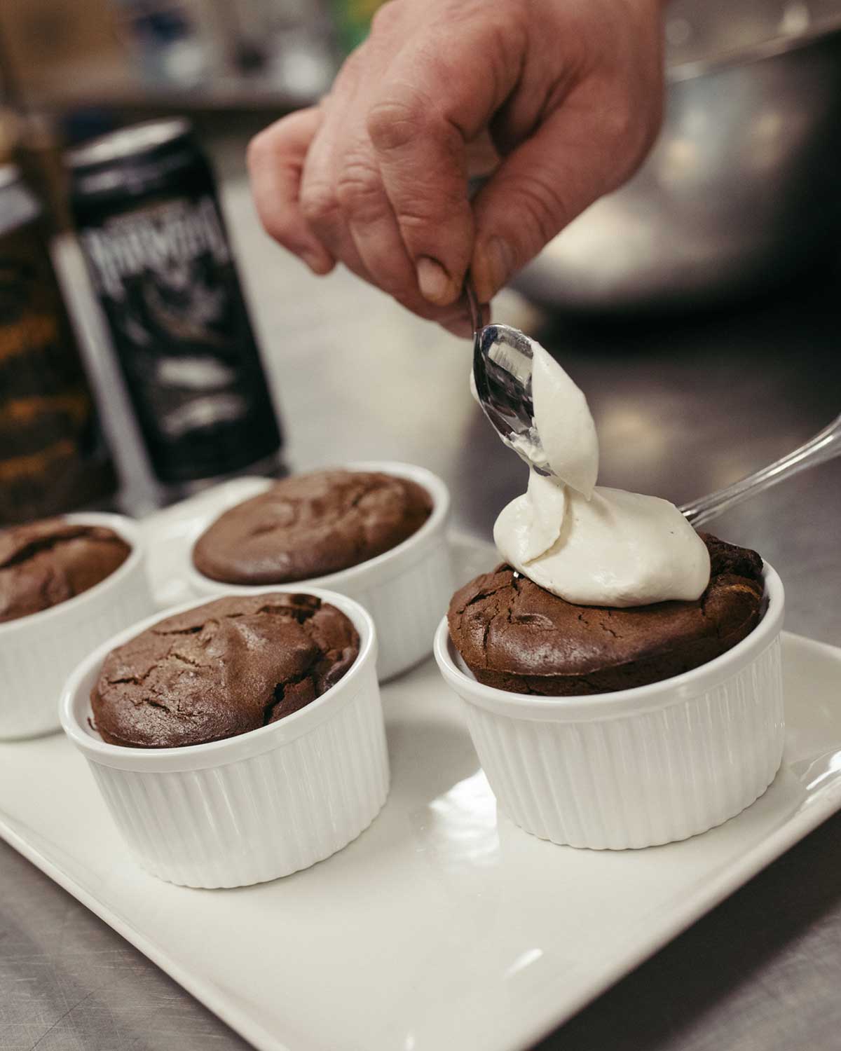 Putting a spoonful of whipped cream on a Barrel-Aged Narwhal flourless cake