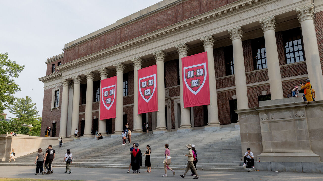 Students are seen walking in front of, as well as standing and sitting on the steps of the Widener Library on the Harvard Campus in Cambridge, Massachusetts, USA.