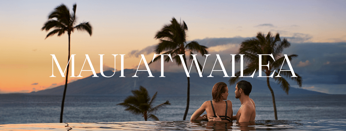 A man and woman looking toward the ocean and a distant island from the edge of an infinity pool; the image includes the text 'Maui at Wailea'.