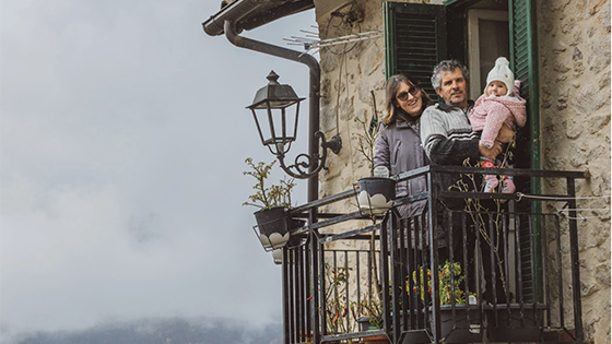 A man and a woman with a baby on a balcony.