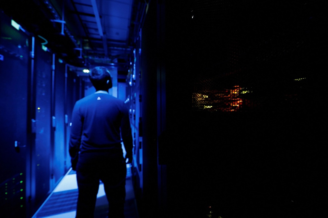 An employee inside a darkly lit data center
