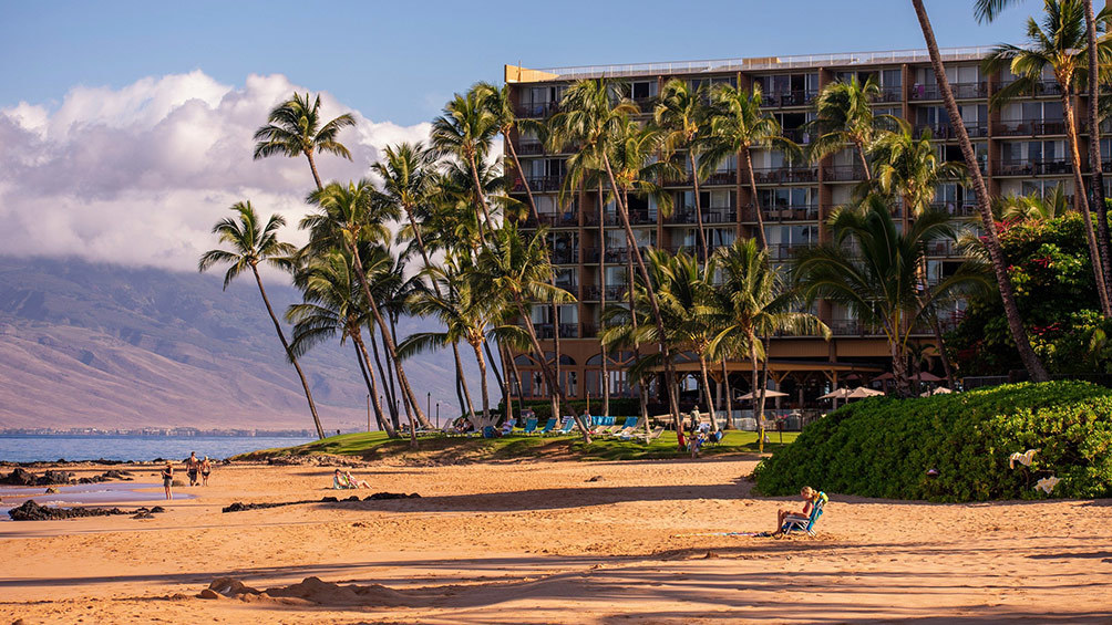 Image description: People relaxing on the beach on Maui in front of a hotel.
