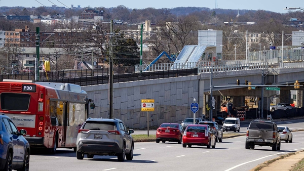 cars and bus drive toward Riverdale Road intersection, with Purple Line construction in background