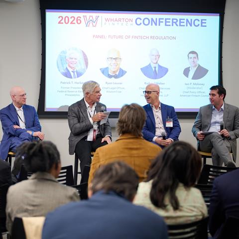 Four panelists in discussion in front of an audience.