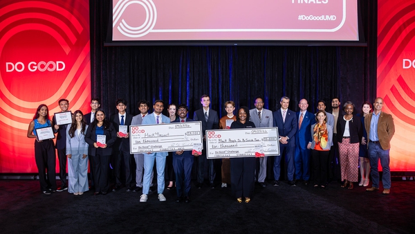 group poses on stage with two giant checks after Do Good Challenge