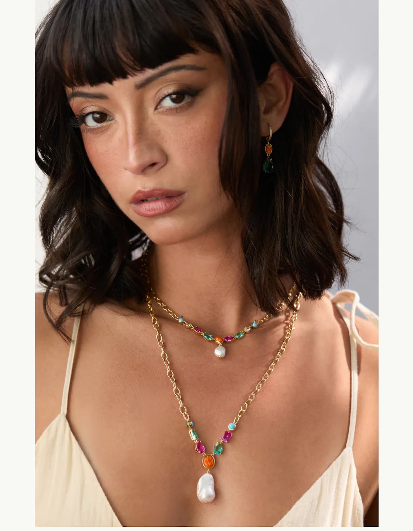 image of model wearing Frieda necklaces with color stones and pearl layered together.