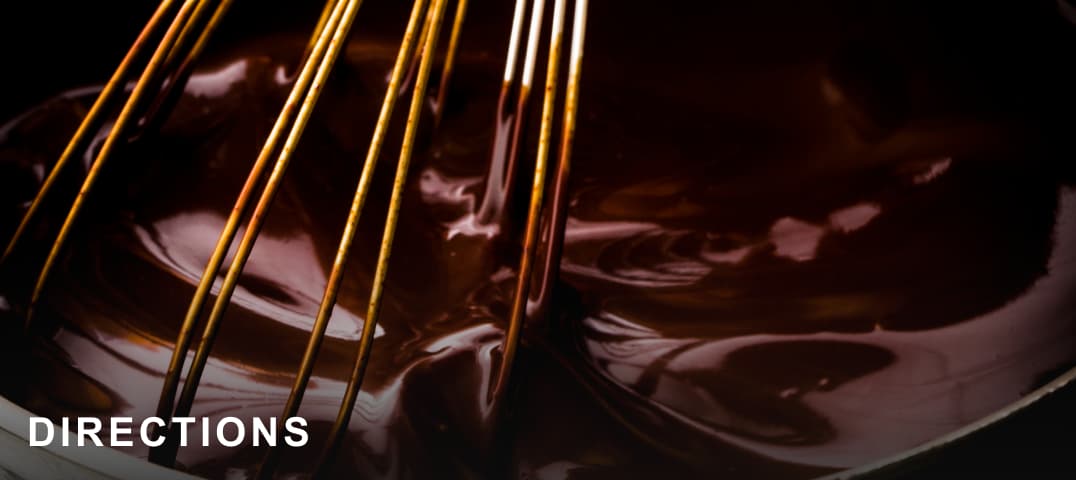 A whisk in a batch of melted chocolate. 