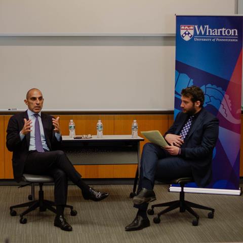 Two speakers engaged in a fireside chat in a classroom