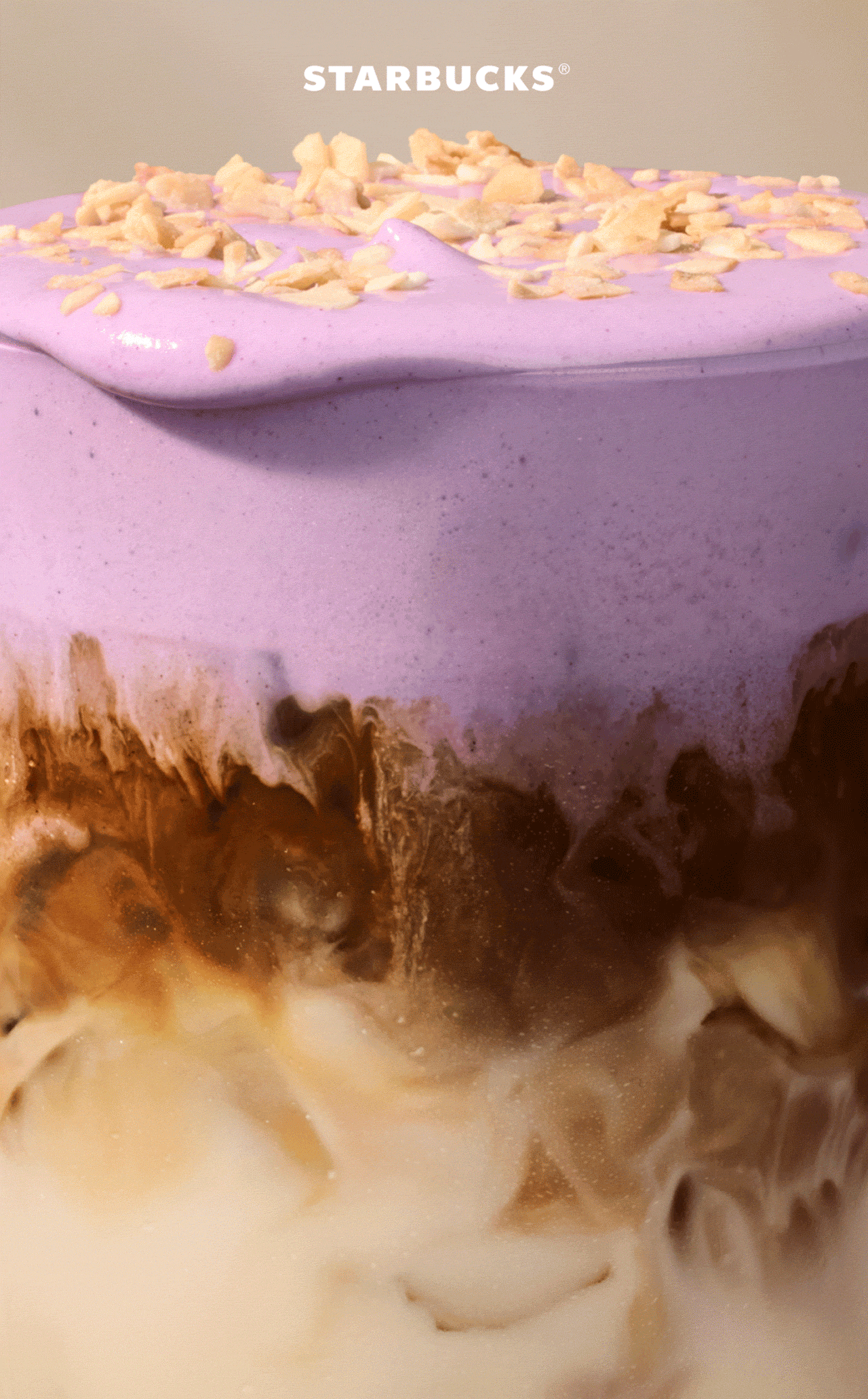 STARBUCKS® | Close-up of an iced macchiato in a glass, with a layer of purple ube cold foam and a sprinkling of coconut flakes. | Ube Coconut Cream Cold Foam & Toasted Coconut Flake Topping | Signature Espresso | Your choice of milk