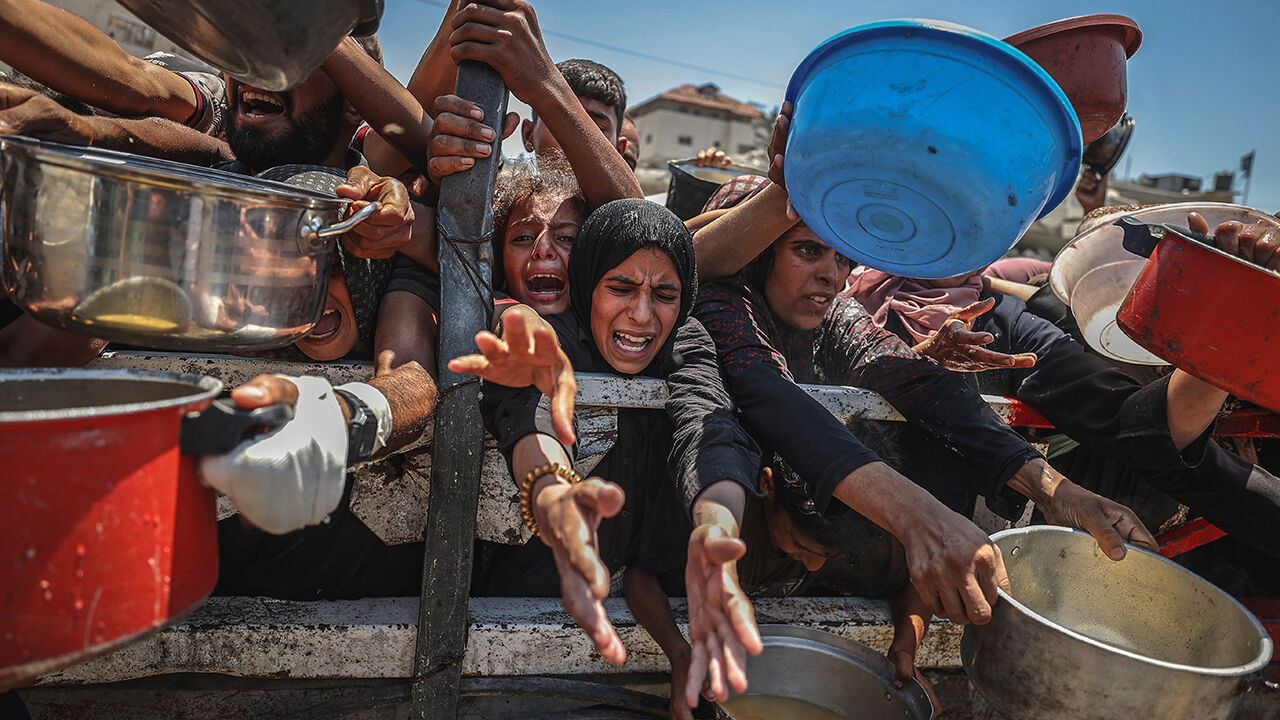 Palestinians reach for food aid at a distribution point in Gaza City