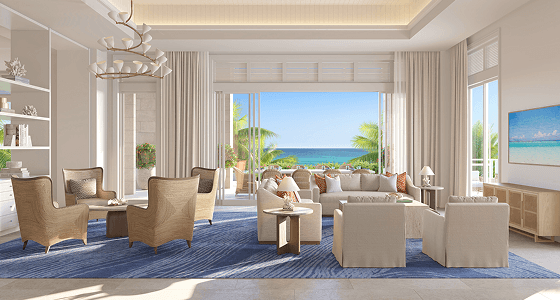 Light-filled living room with lounge seating and floor-to-ceiling doors opening onto a terrace with ocean views.