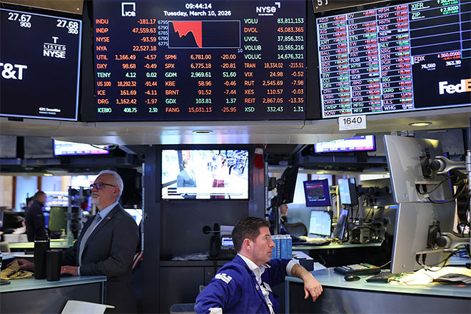 Stockbrokers working beneath a chart of the stock market on Wall Street.