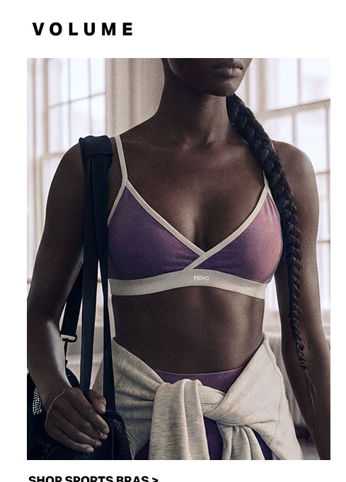 Woman with a braid models a purple sports bra with white trim, carrying a gym bag. Explore our comfortable activewear and sports bra collection.