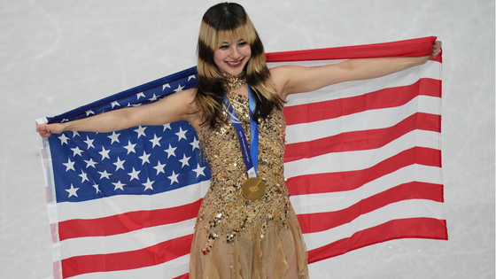 A woman poses on the ice with the American flag.
