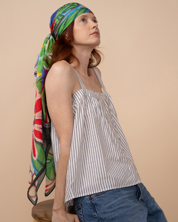 Welcome to Echo! A model wearing the Celebrate Oversized Square as a head wrap is lost in thought.
