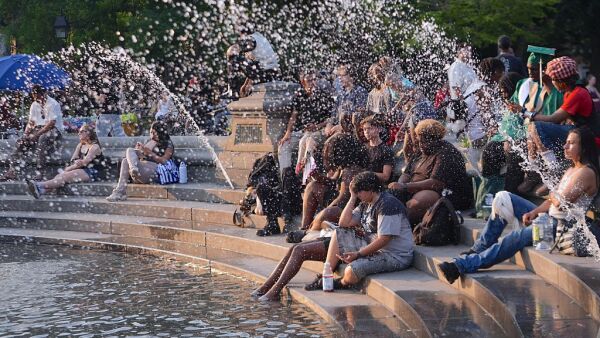 People sit on steps by the water at Washington Square Park.