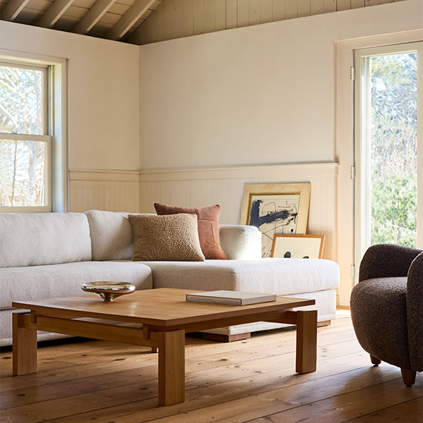 A living room with a large gray sectional couch, low wooden coffee table, and brown boucle chair.