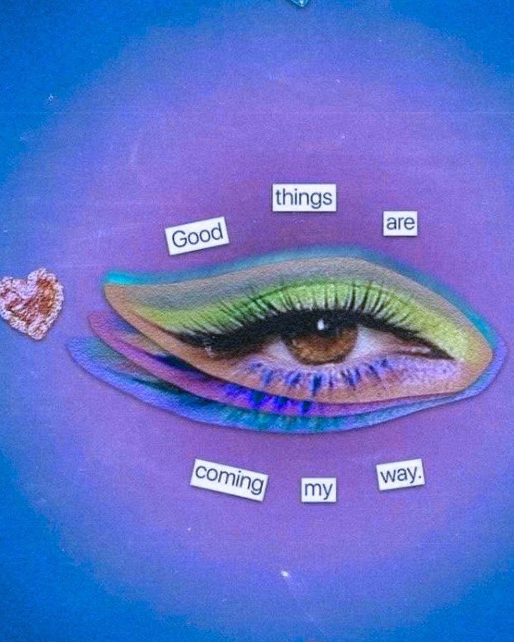 On a blue and purple background, a collage of a brown eye with green makeup is surrounded by the words: Good things are coming my way. 